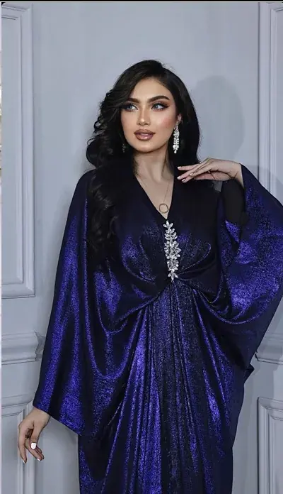 Model in a sapphire shimmer-velvet kaftan with batwing sleeves and a crystal brooch at the waist
