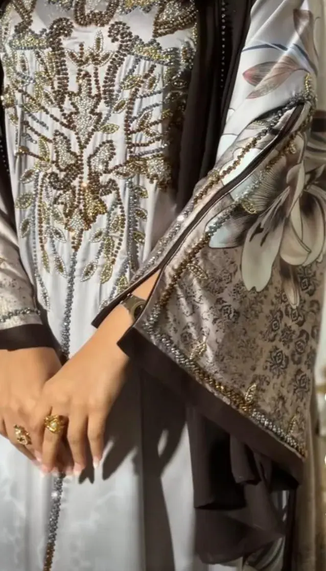 Close-up of an ivory kaftan with gold and floral print and a beaded front panel