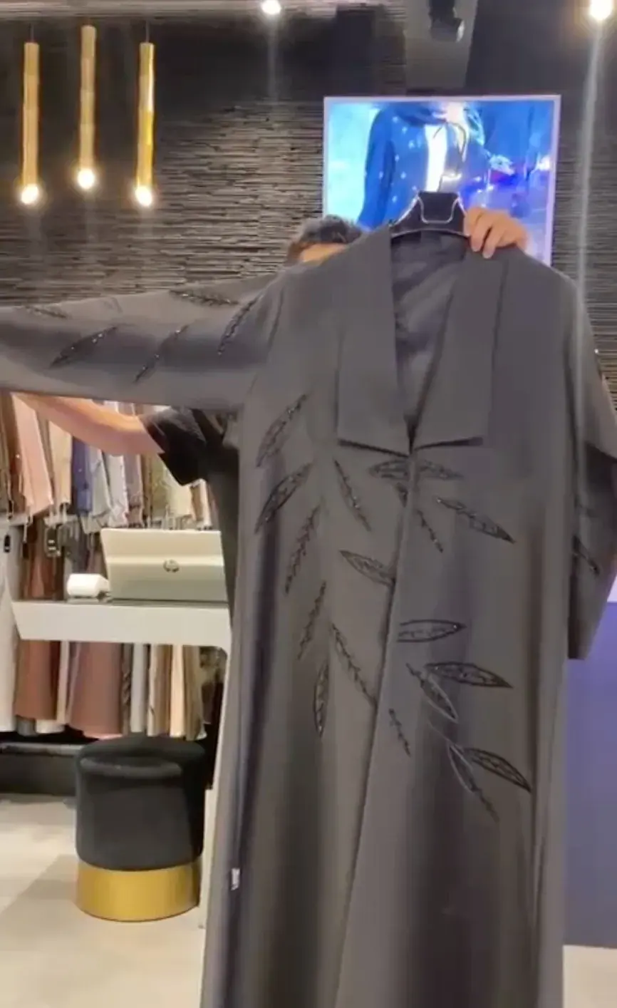Grey abaya with a wide collar and bamboo-leaf embroidery, shown on a hanger