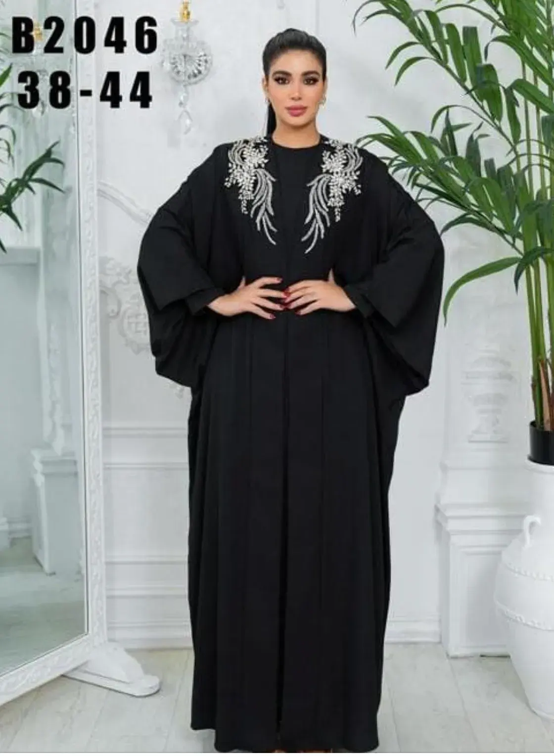 Model in a black butterfly-sleeve abaya with crystal wings embroidered at the shoulders