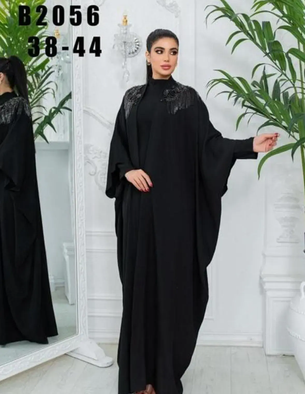 Model in a black butterfly abaya with a high neck and an embellished shoulder
