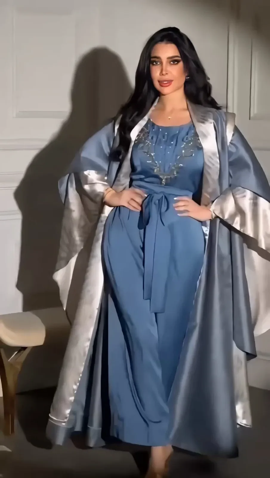 Model in a steel-blue satin dress with a jewelled neckline under a silver-lined open cape