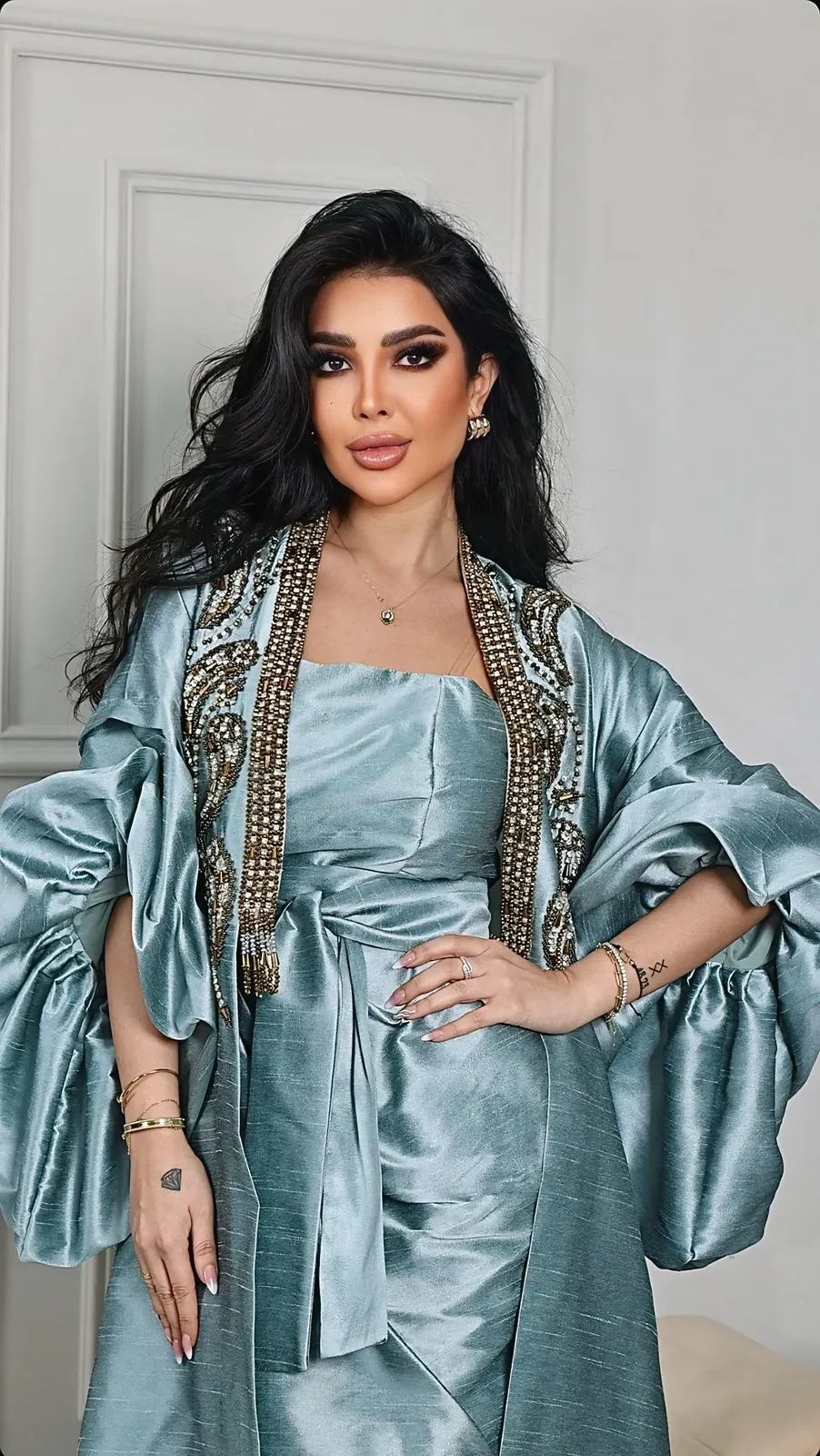 Model in an aqua satin dress with a beaded open bolero and volume sleeves