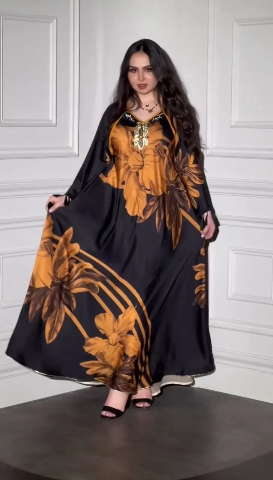 Model in a black satin kaftan with large amber floral print