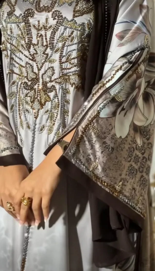 Close-up of an ivory kaftan with gold and floral print and a beaded front panel