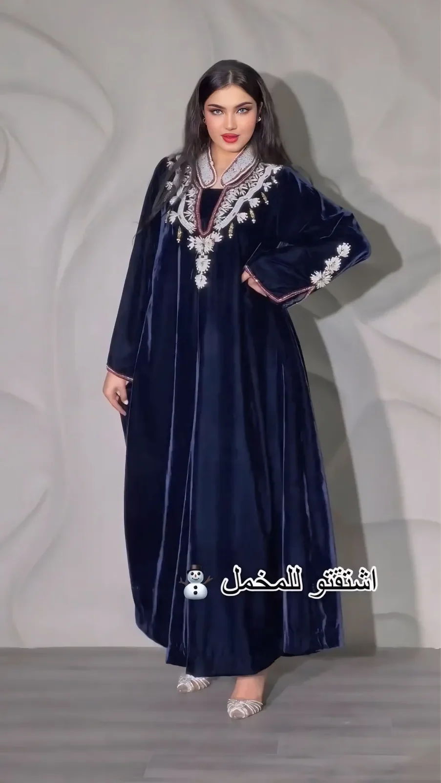 Model in a midnight-navy velvet jalabiya with silver floral embroidery