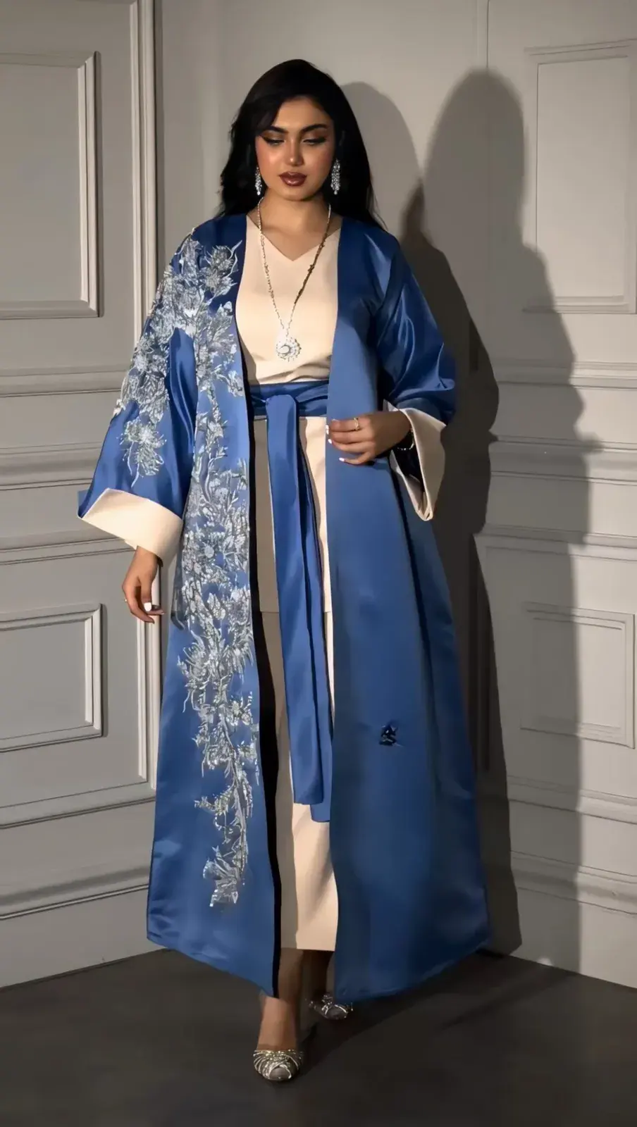 Model in a royal-blue satin robe with silver embroidery over a cream dress